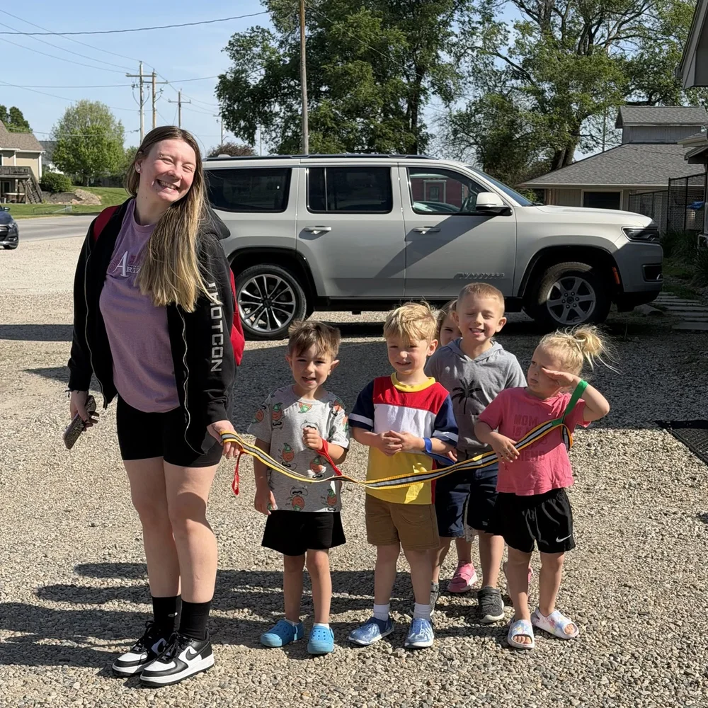 Nest staff member walking a line of preschoolers to the vehicle for wrap-around transportation to Earlham Community School