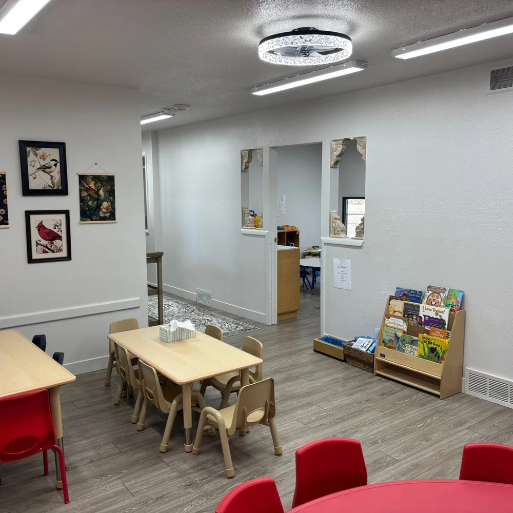 Dining and reading area with child-size tables, a book display, and framed bird artwork