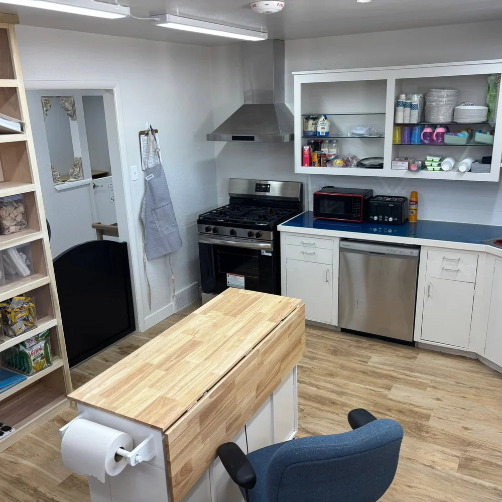 Kitchen prep area with stove, prep island, and stocked shelves for homemade meals at The Nest