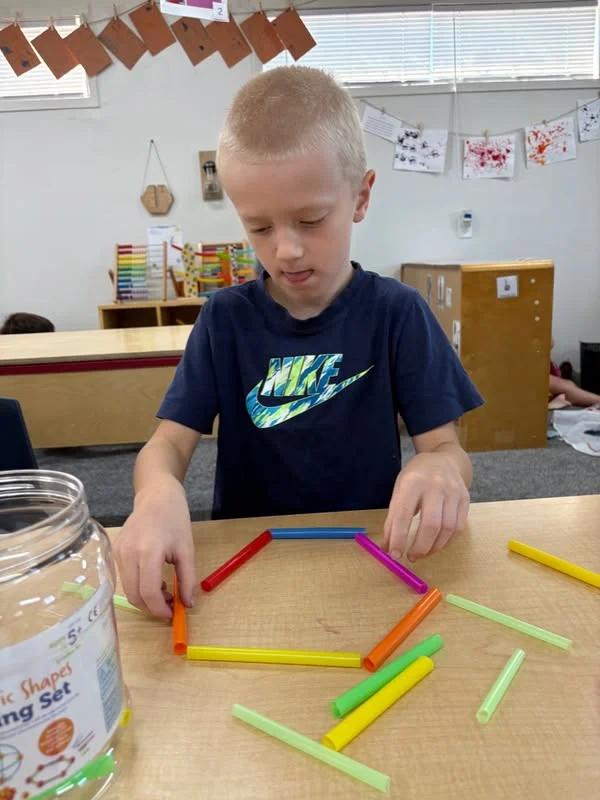 School age boy constructing a large shape from building straws at The Nest