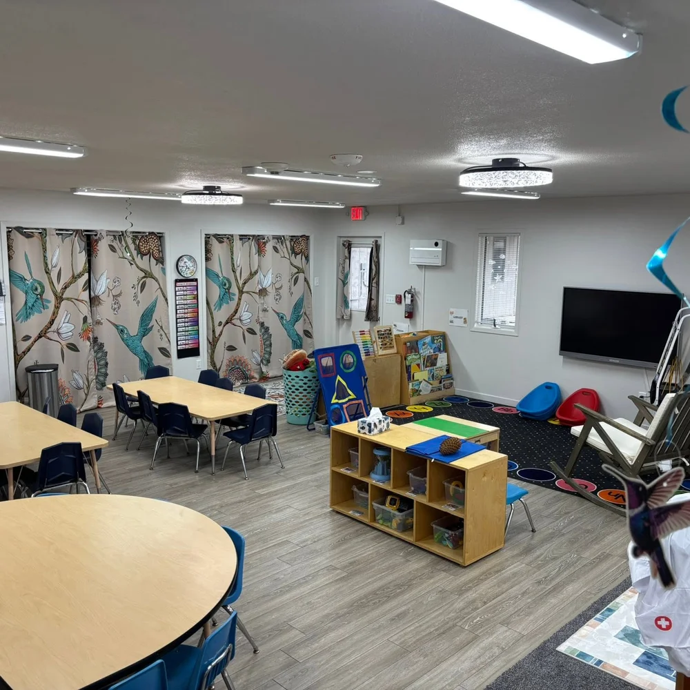 Hummingbirds preschool classroom with hummingbird curtains, tables, and a reading library