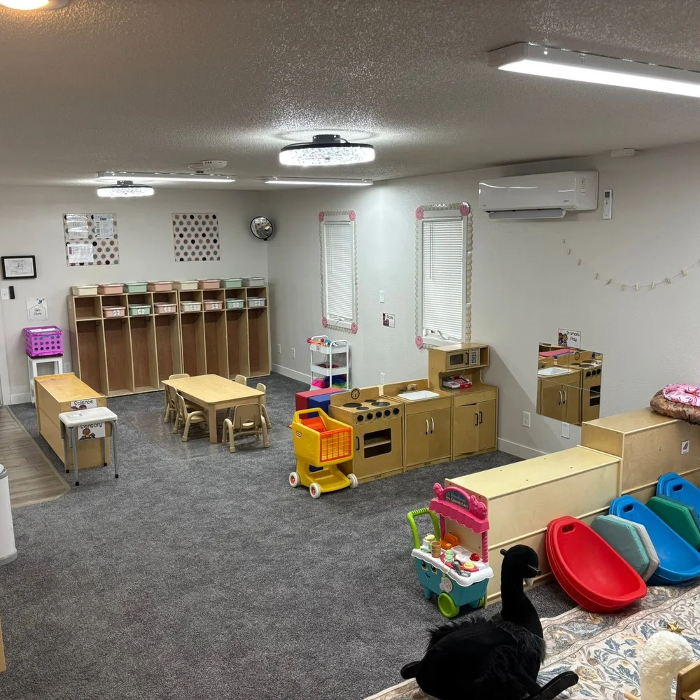 Chickadees toddler room with cubbies, child-size tables, and a dramatic play kitchen
