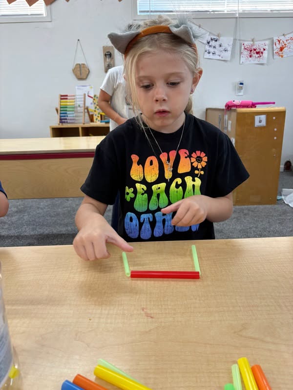 Girl connecting straws into shapes during a school age learning activity at The Nest