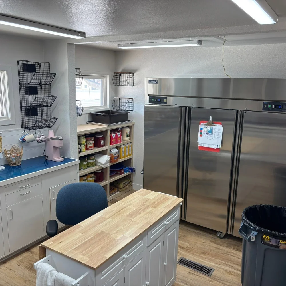 Kitchen storage area with commercial refrigerators and a stocked pantry for fresh daily meals