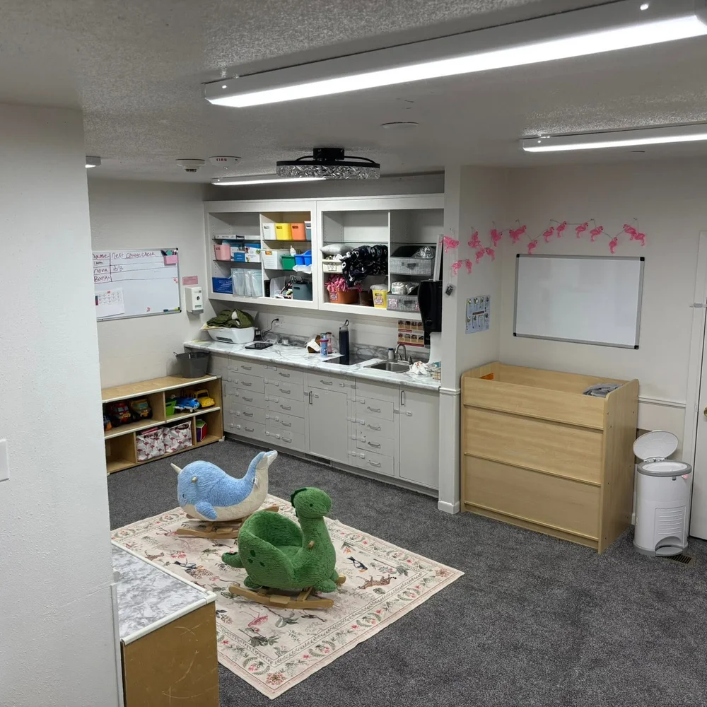 Flamingos infant transition room with rocking animals, changing station, and open play space